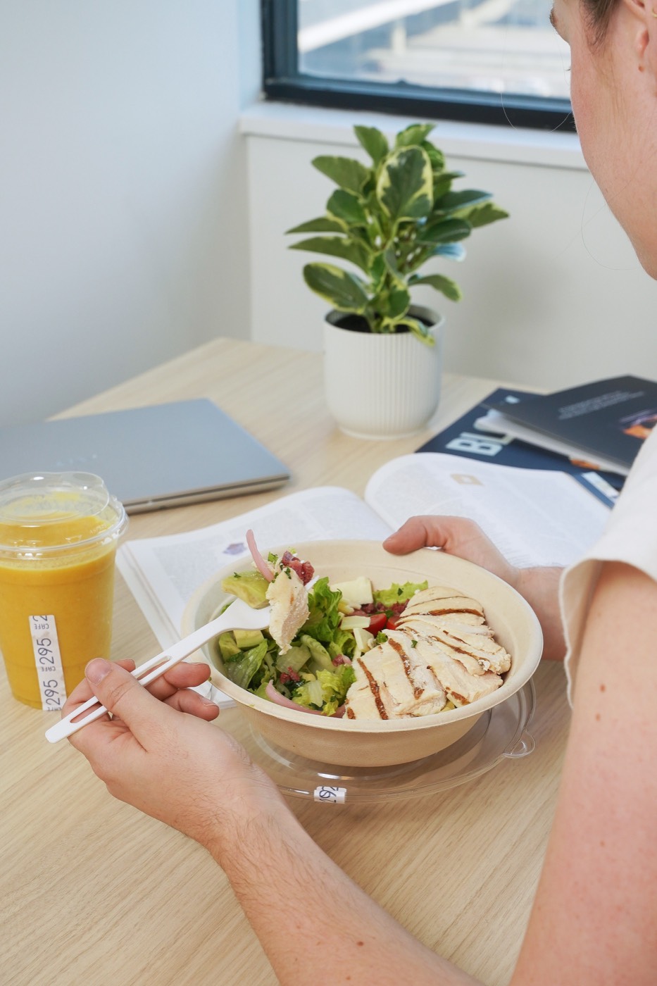 Guest working at a window table with a bowl and an iced drink